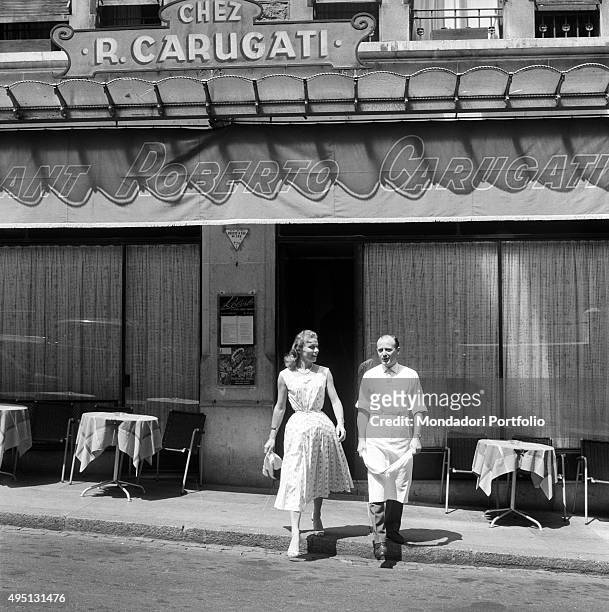 Restaurateur and chef Roberto Carugati walking beside his wife Paola in front of his restaurant in La Madeleine, Geneva, 18th July 1955. The city is...