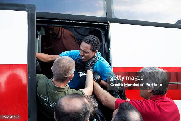 Policemen pushing into a bus a migrant protesting against the evacuation. African migrants have created makeshift shelters in Ventimiglia, the last...