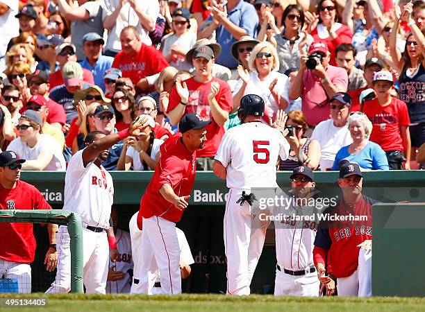 Jonny Gomes of the Boston Red Sox is congratulated by teammates in the dugout after scoring in the fourth inning against the Tampa Bay Rays during...