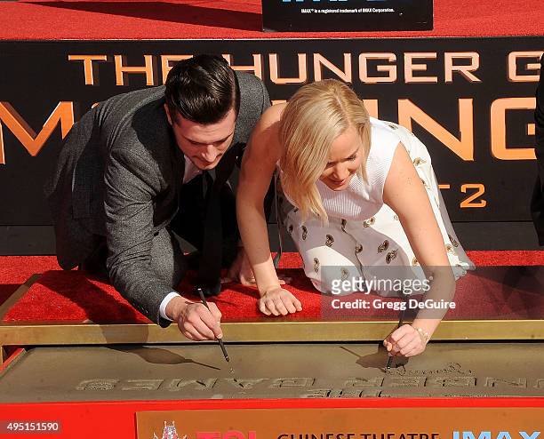 Actors Josh Hutcherson and Jennifer Lawrence pose at "The Hunger Games: Mockingjay - Part 2" Hand And Footprint Ceremony at TCL Chinese Theatre on...