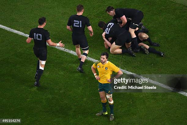 Adam Ashley-Cooper of Australia stands dejected as Beauden Barrett of the New Zealand All Blacks is congratulated by teammates on scoring his sides...