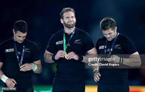 Dan Carter, Kieran Read and Richie McCaw of New Zealand inspect their winning medals following the 2015 Rugby World Cup Final match between New...