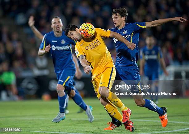 Luis Suarez of FC Barcelona competes for the ball with Santiago Vergini of Getafe CF and his teammate Damian Suarez during the La Liga match between...