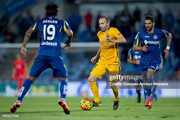 Andres Iniesta of FC Barcelona controls the ball between Angel Lafita of Getafe CF and his teammate Damian Suarez during the La Liga match between...