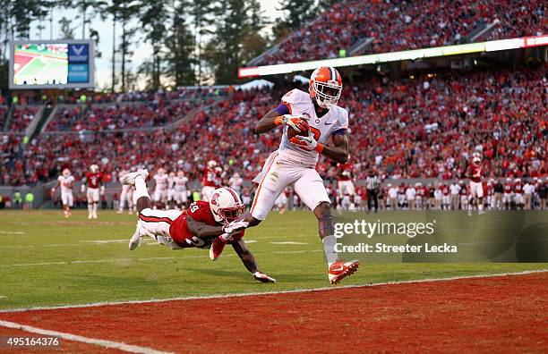 Deon Cain of the Clemson Tigers catches as touchdown pass as Jack Tocho of the North Carolina State Wolfpack dives to try to stop him during their...