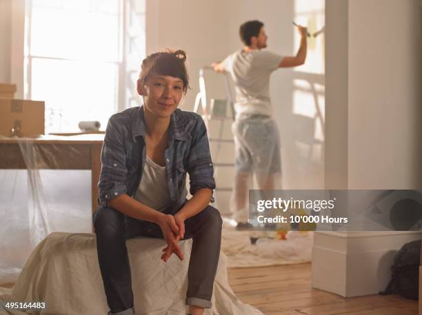 portrait of happy mixed race woman in her new home - couple painting stock pictures, royalty-free photos & images