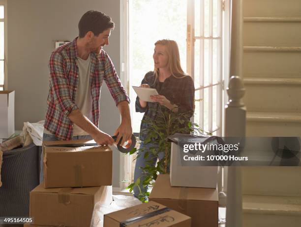 a couple moving home, the woman is using an tablet computer - couple tablet house stock-fotos und bilder