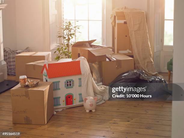 room with packing boxes dolls house and piggybank - morgage stockfoto's en -beelden