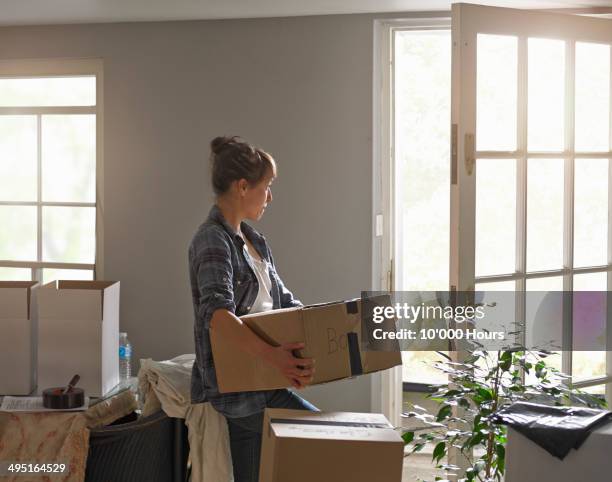 a woman carrying boxes whilst moving home - woman on the move stock pictures, royalty-free photos & images