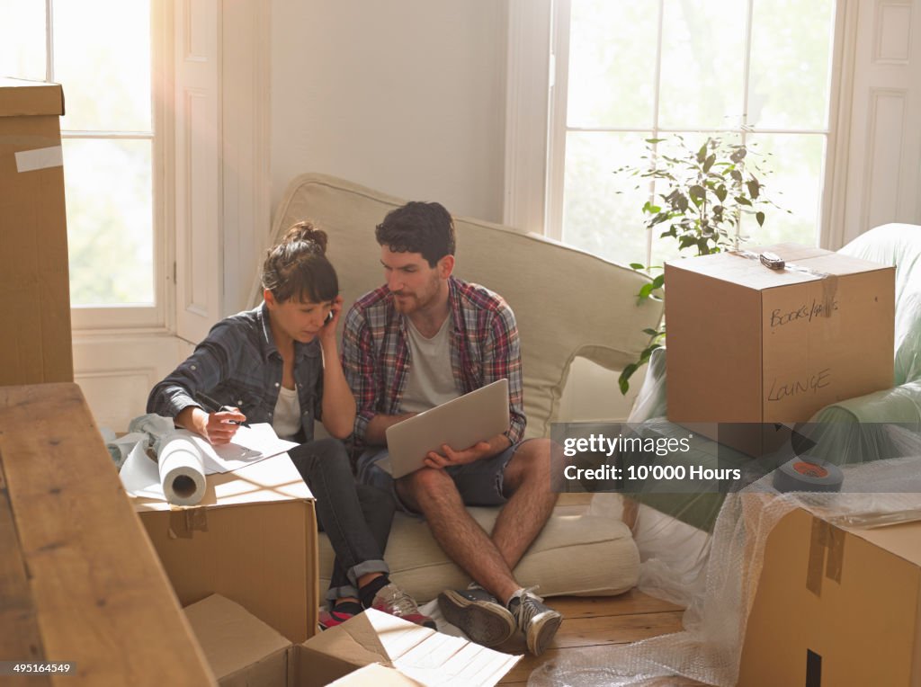 Couple moving into new home working on a laptop
