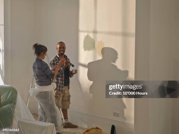 a man and woman doing diy in new home - couple painting stock-fotos und bilder