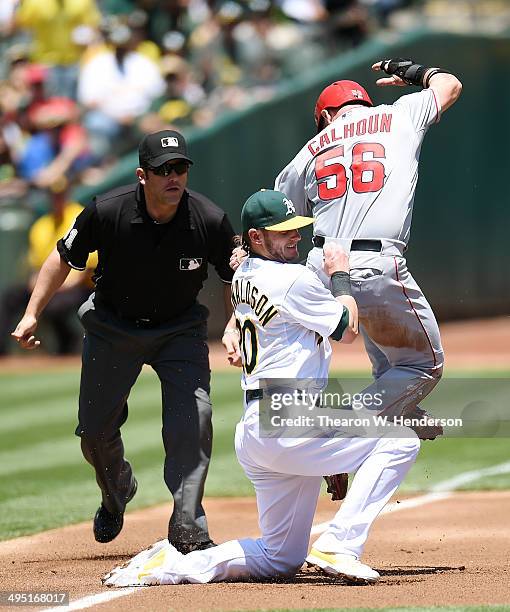 Kole Calhoun of the Los Angeles Angels of Anaheim gets tagged out at third base by Josh Donaldson of the Oakland Athletics in the top of the first...