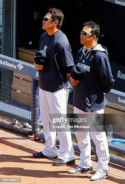 Masahiro Tanaka and Hiroki Kuroda of the New York Yankees stand during the playing of 'God Bless America' during the seventh inning against the...