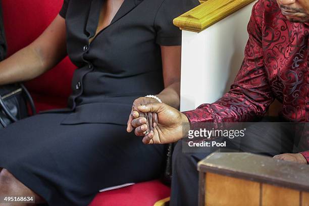 In this handout photo provided by the Palm Beach Post, A man and a woman hold hands as the congregation prays during the funeral for Corey Jones at...