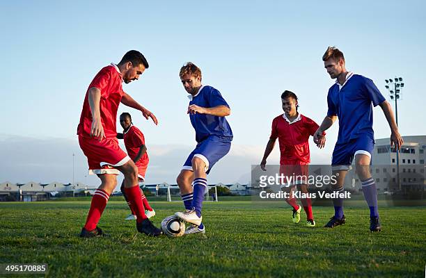 football players tackling the ball on the field - soccor games stockfoto's en -beelden