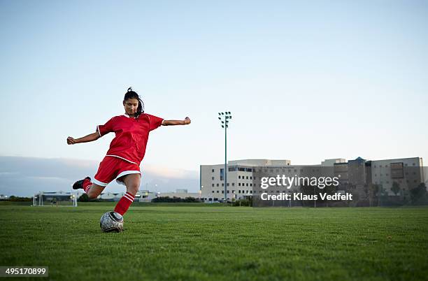 female football player striking the ball on field - urban football pitch stock pictures, royalty-free photos & images