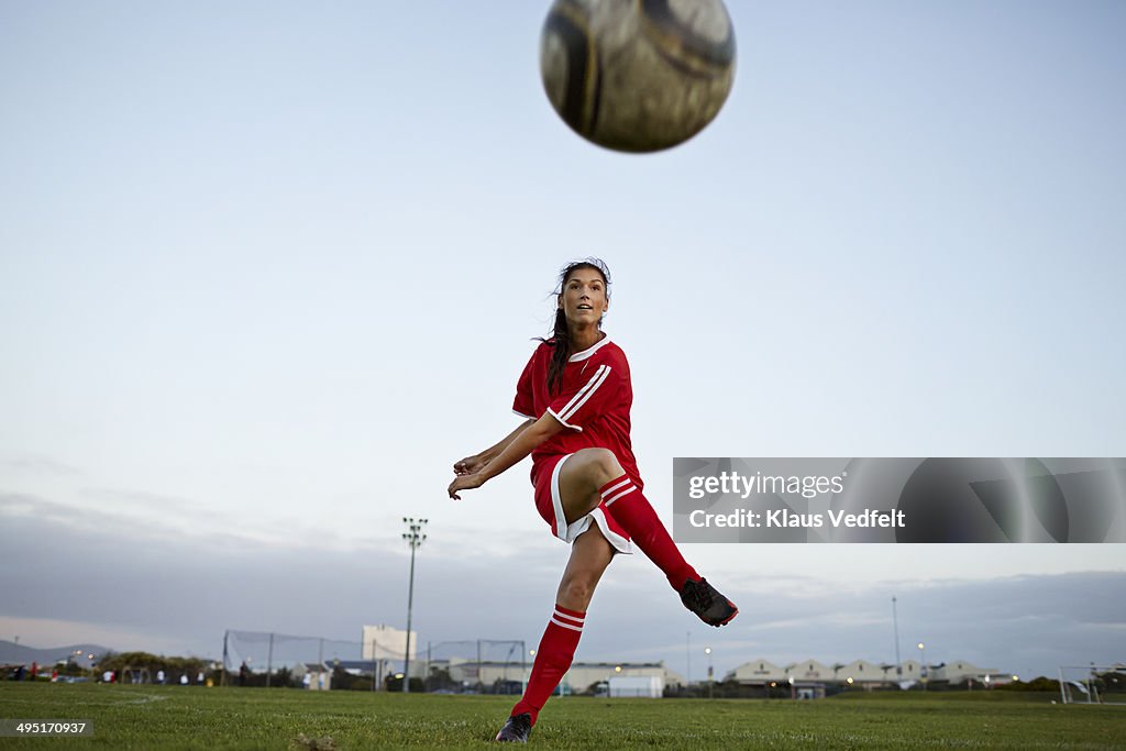 Female soccer player kicking the ball over camera