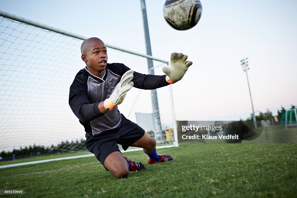 Goalkeeper jumping out to catch football