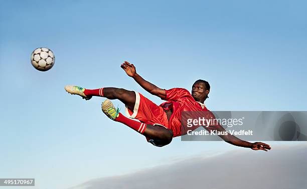 football player about to kick ball in the air - fußballspieler stock-fotos und bilder