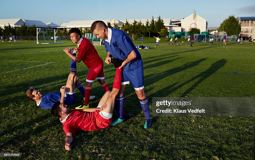 Teammates stretching together on football field