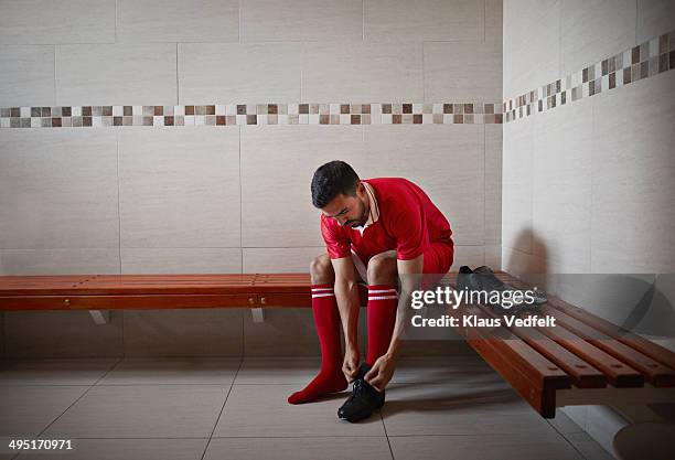 football player tying shoe, alone in changing room - locker room foto e immagini stock