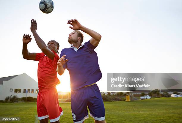 soccer players battling to head the ball - heading the ball stockfoto's en -beelden