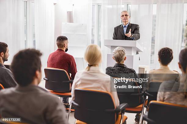 senior businessman giving a speech on a conference. - board room background stock pictures, royalty-free photos & images