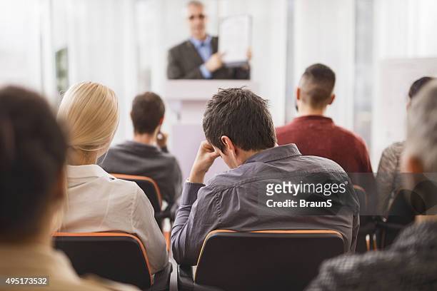 back view of exhausted businessman attending an education event. - bores stock pictures, royalty-free photos & images