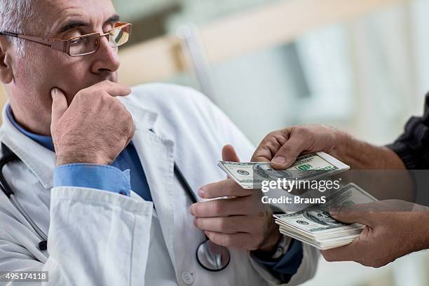 close up of a mature doctor receiving bribery. - bribing stockfoto's en -beelden