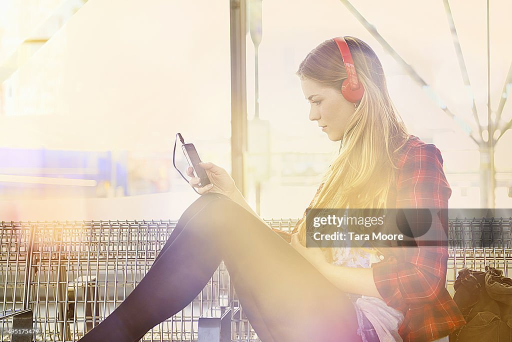 Woman at station listening to music with mobile