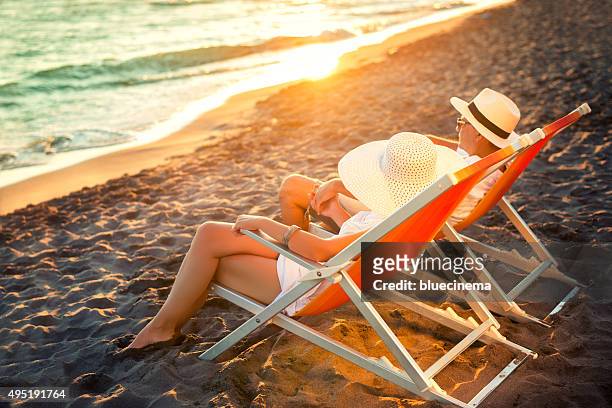 feliz pareja en la playa - man on the beach relaxing in deckchair fotografías e imágenes de stock
