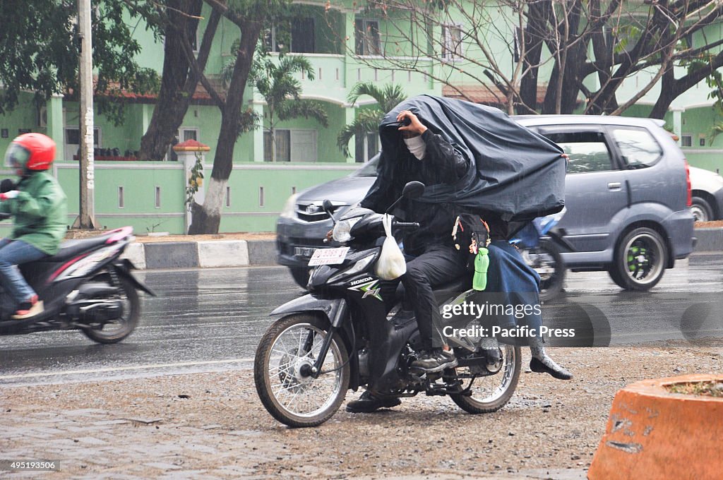 Motorcycle riders try to cover themself from rain in Kapasa...