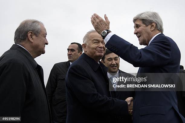 Uzbek Foreign Minister Abdulaziz Kamilov looks on while Uzbek President Islam Karimov and US Secretary of State John Kerry shake hands at Samarkand...