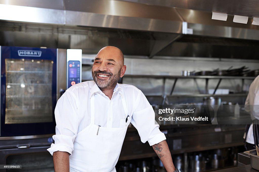 Chef standing in kitchen laughing