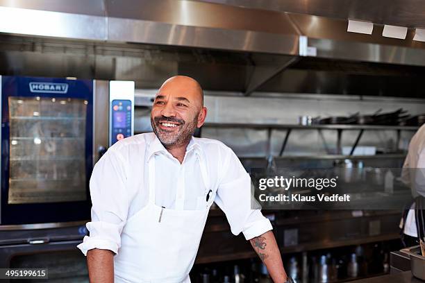 chef standing in kitchen laughing - restaurateur photos et images de collection