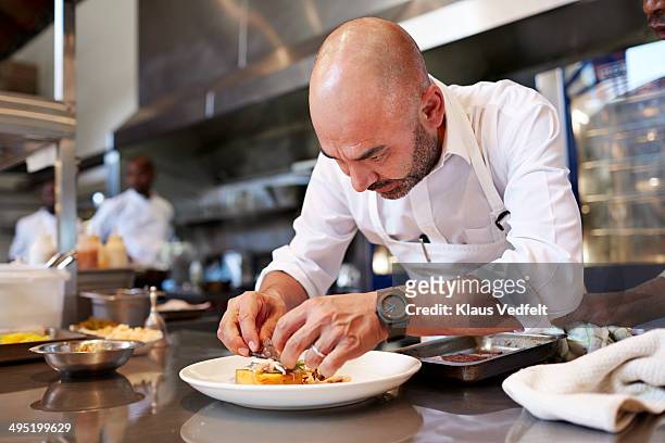 head chef finishing dish in kitchen at restaurant - chef foto e immagini stock