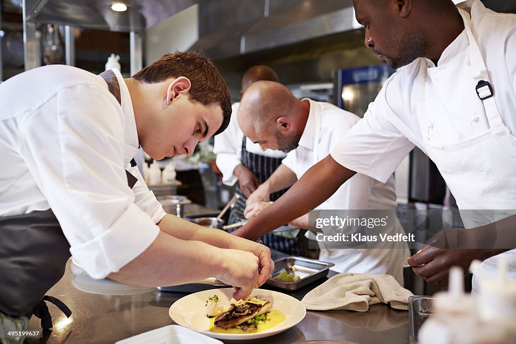 Chefs preparing dishes in kitchen at restaurant