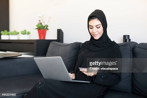 content arab woman shopping online being at home - arab shopping stockfoto's en -beelden