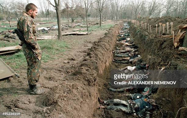 Russian Army soldier inspects 31 March 1995 at a cemetery in Grozny, capital of the breakaway southern republic of Chechnya, the bodies of Chechen...