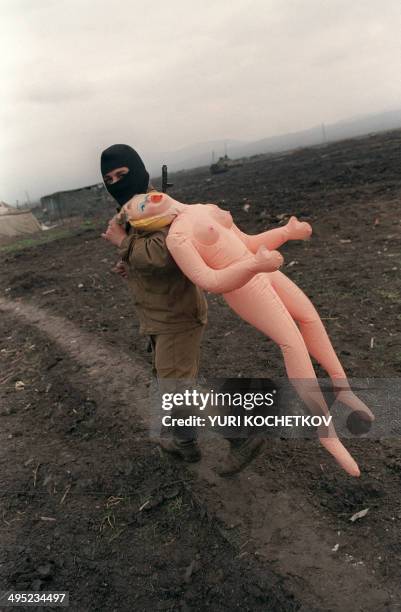 Russian soldier carries an inflatable doll in Shali, 14 April 1996 during a break in the battle with Chechen rebels. AFP PHOTO YURI KOCHETKOV