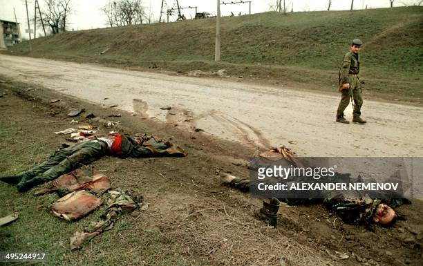 Chechen rebel passes 03 March 1996 by the bodies of Russian soldiers in Grozny, capital of the breakaway southern republic of Chechnya. Chechen...