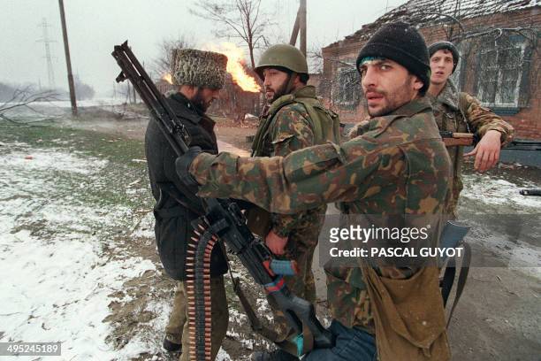 Chechen fighter checks his weapon while chatting with some comrades on January 17, 1995 on the outskirts of Grosny in the breakaway Republic of...