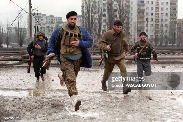 Chechen fighters run across the street, trying to avoid sniper fires as they head for the presidential palace in dowtown Grozny on January 12, 1995....