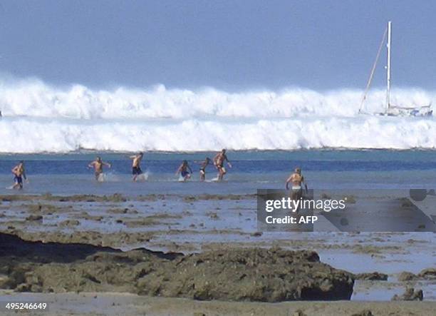 Foreign tourists far out on the sand after the water receeded react as the first of six tsunami start to roll towards Hat Rai Lay Beach, near Krabi...