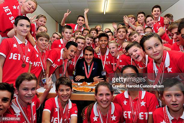 Roger Federer of Switzerland hands out pizza as he celebrates with the ball boys winning the final match of the Swiss Indoors ATP 500 tennis...