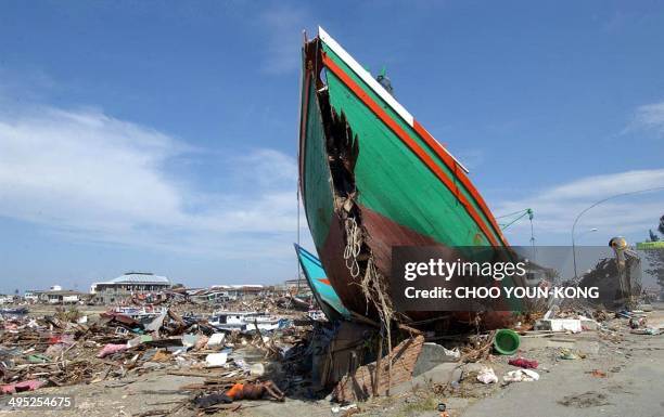 Dead body lies under a fishing boat which was swept into land by a tsunami in the port area of Banda Aceh, 30 December 2004. The Indonesian death...