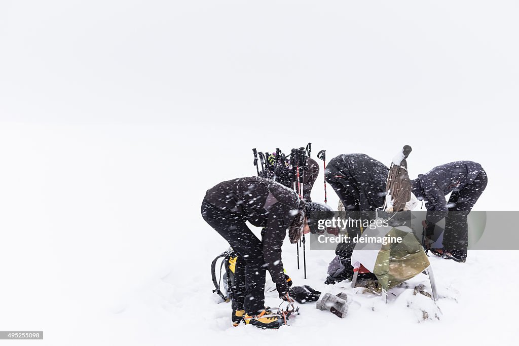 Climbers put crampons on boots