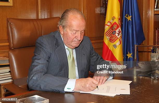 In this handout image provided by the Spanish Royal Palace, King Juan Carlos of Spain signs papers to confirm his abdication on June 02, 2014 in...