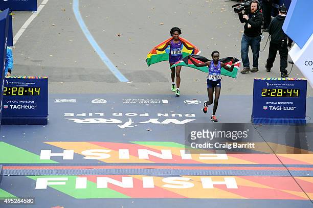 Mary Keitany of Kenya runs alongside third place Tigist Tufa of Ethiopia after the Pro Women's division at TAG Heuer Official Timekeeper and...