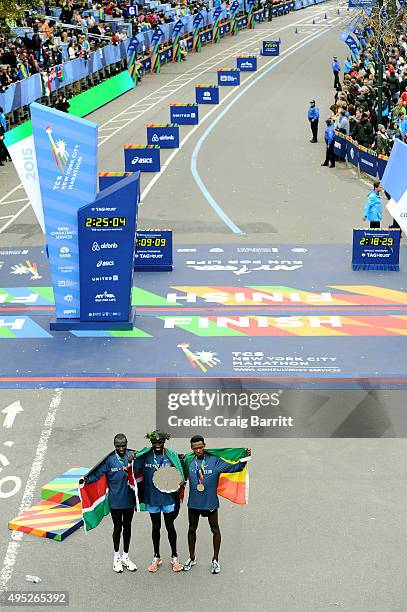 Stanley Biwott of Kenya poses with the first place trophy alongside second place Geoffrey Kipsang Kamworor of Kenya and third place Lelisa Desisa of...